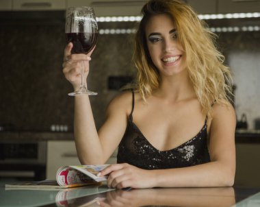Evde bir kadeh şarapla çekici genç bir kadın.