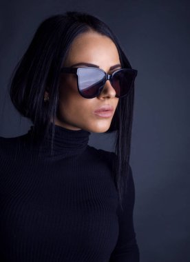 Çekici esmer kadın kameraya güneş gözlüklü poz veriyor.