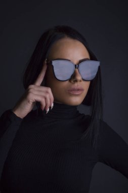 Çekici esmer kadın kameraya güneş gözlüklü poz veriyor.