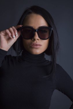 Çekici esmer kadın kameraya güneş gözlüklü poz veriyor.