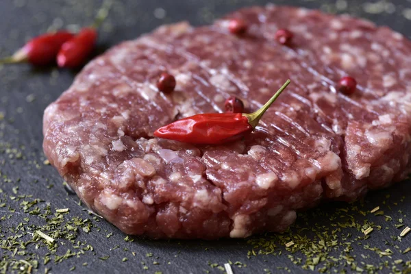 Raw burger on a slate surface — Stock Photo, Image