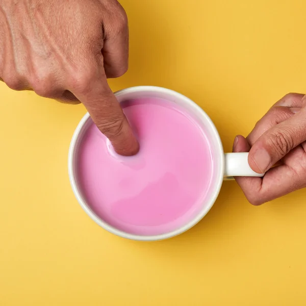 Człowiek, moczenie palca swego w różowy milkshake — Zdjęcie stockowe