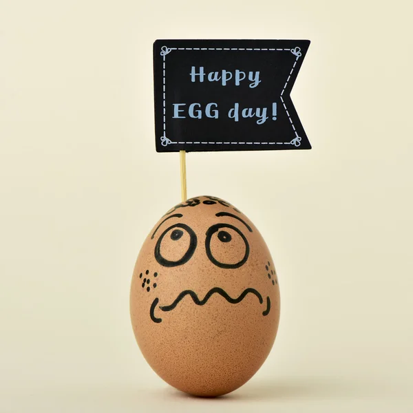 Huevo con un cartel con el texto feliz día del huevo — Foto de Stock