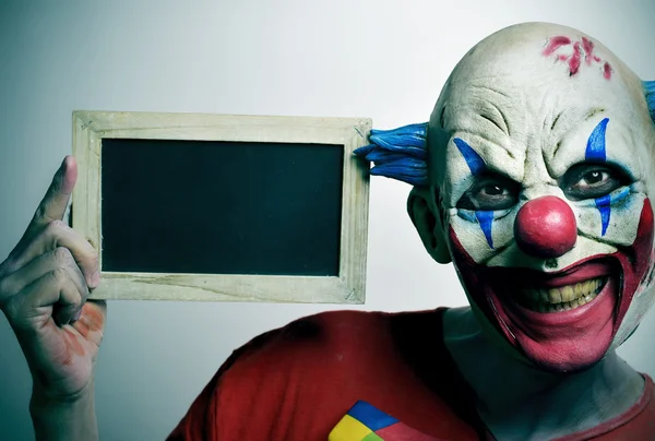 Böser Clown mit leerer Tafel — Stockfoto