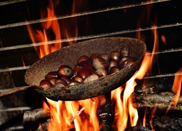 Arrostimento di castagne tra le fiamme di un fuoco a legna — Foto Stock