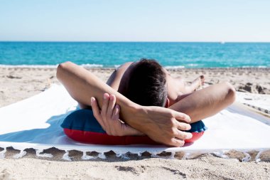 young man sun tanning on the beach clipart