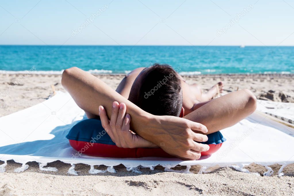 young man sun tanning on the beach