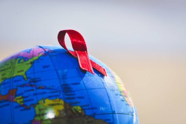 world globe with a red ribbon for the fight against AIDS clipart