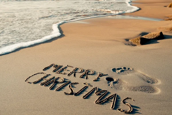 Texto Feliz Natal na areia de uma praia — Fotografia de Stock