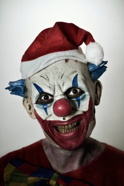 scary evil clown with a santa hat clipart