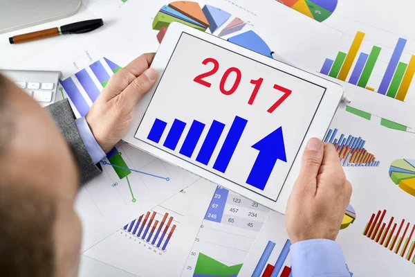 Hombre observando un pronóstico económico para 2017 en su tableta — Foto de Stock