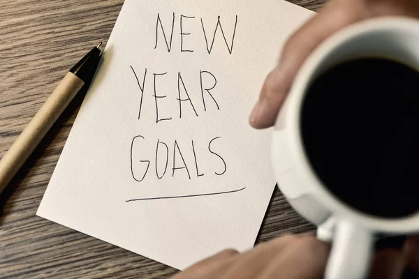 Man having a coffee and text new year goals — Stock Photo, Image