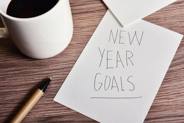 Cup of coffee and text new year goals — Stock Photo, Image