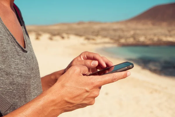 Jonge man met behulp van een smartphone naast de zee — Stockfoto