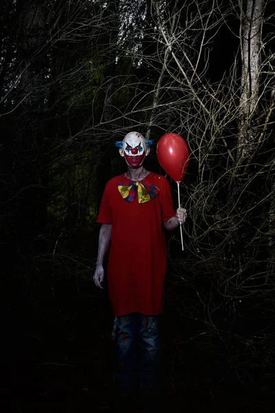 Skrämmande onda clown i skogen på natten — Stockfoto