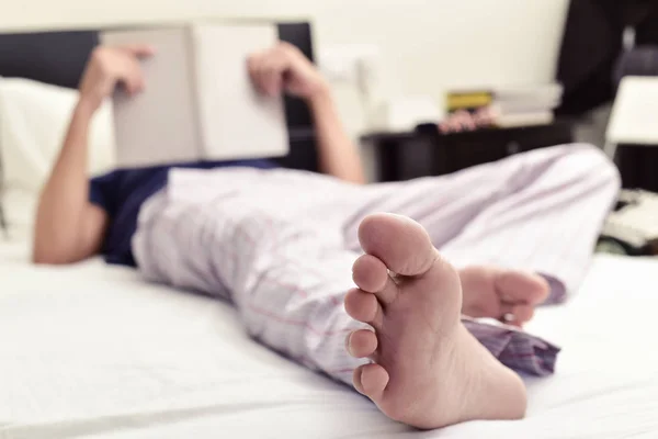 Молодой человек читает книгу в постели — стоковое фото