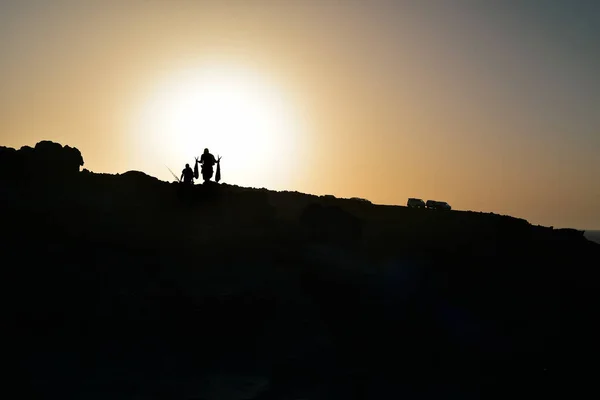 Silhouette von Fischern auf einer Klippe in der Abenddämmerung — Stockfoto