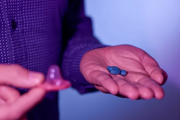 Young man with blue pills and condom — Stock Photo, Image