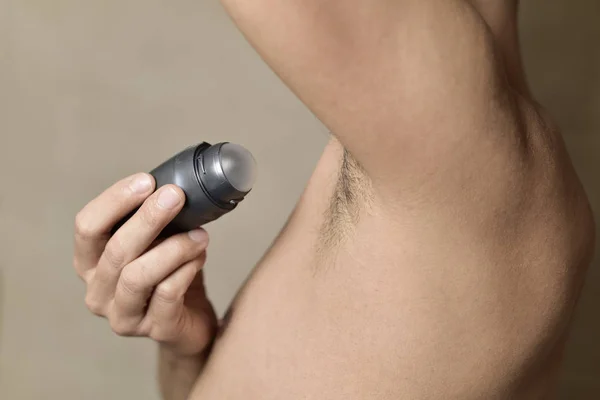 Genç adam onun koltukaltı deodorantı uygulama — Stok fotoğraf