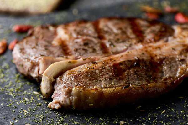 Closeup of a grilled strip steak seasoned with different spices served on a slate tray