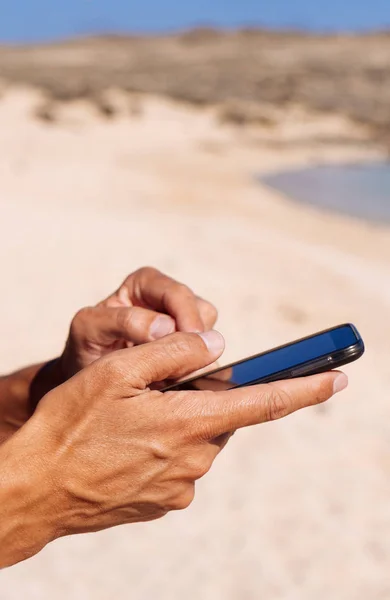 Denizin yanında bir akıllı telefon kullanan genç adam — Stok fotoğraf