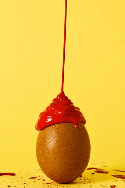 Красная краска на коричневом яйце — стоковое фото