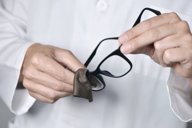 optician man cleaning a pair of eyeglasses clipart