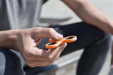 young man playing with a fidget spinner clipart