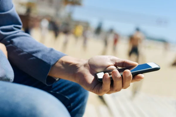 Людина використовує смартфон поруч з пляжем — стокове фото