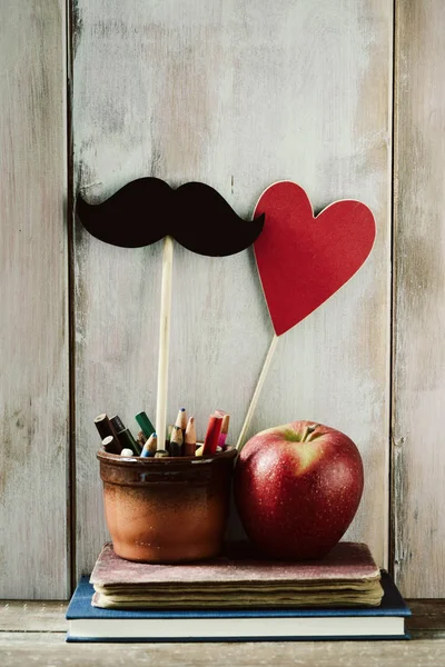 Moustache, heart, pencils, apple and books — Stock Photo, Image