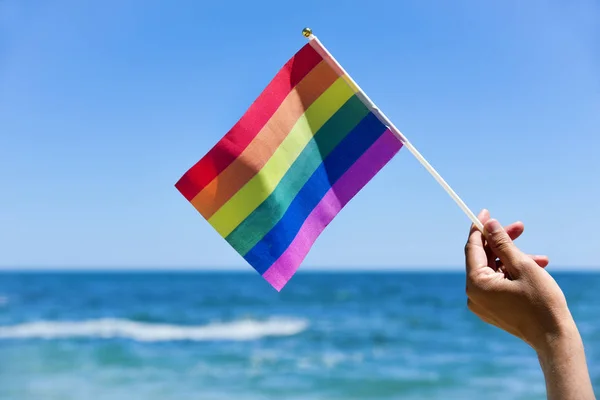 Hombre ondeando una pequeña bandera de arco iris — Foto de Stock