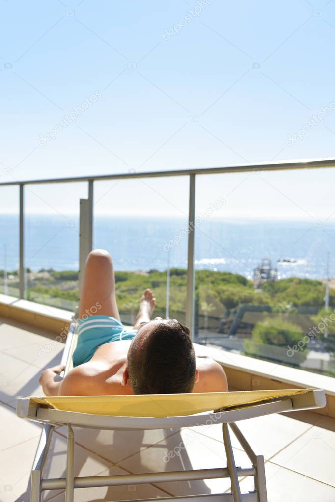 young man sun tanning in a sunlounger