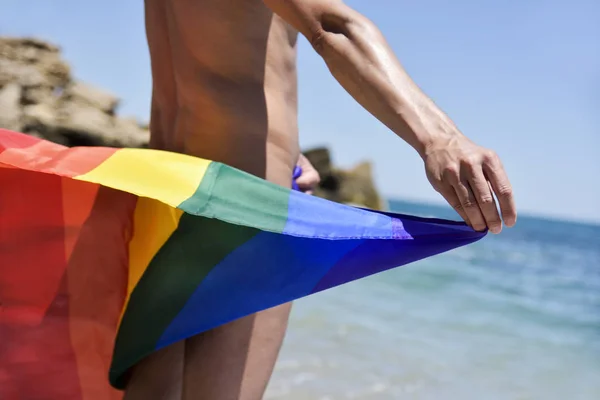 Homem com uma bandeira do arco-íris na praia — Fotografia de Stock