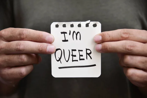 Молодой человек с запиской с текстом I am queer — стоковое фото