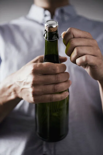 Young man opening a bottle of champagne — Stock Photo, Image