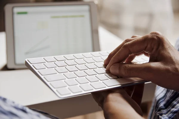 Joven en pijama escribiendo en un teclado — Foto de Stock