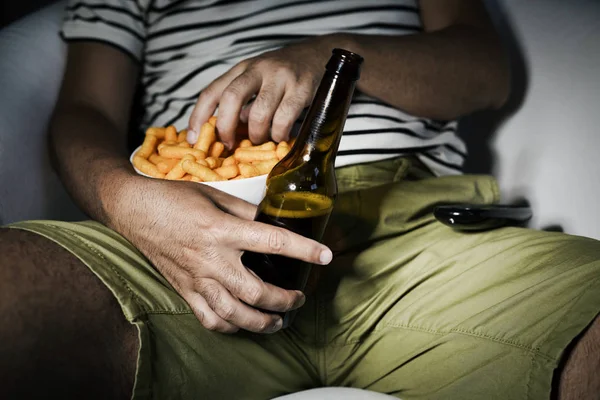 Mann trinkt Bier und isst Käsepuffer — Stockfoto