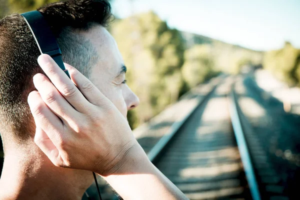 Jonge man met een koptelefoon op de railroad tracks — Stockfoto