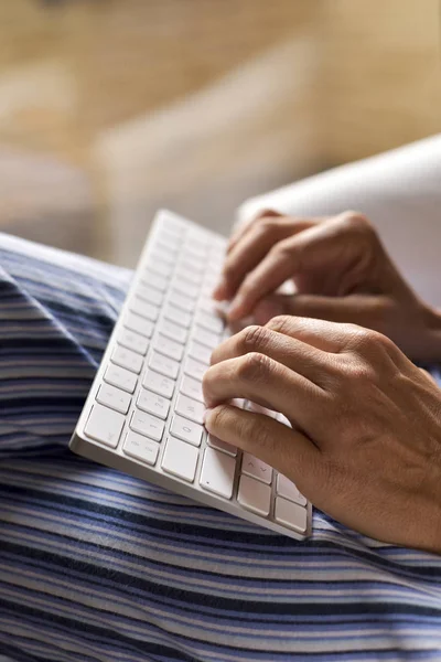 Young man in pajamas typing in a keyboard — Stock Photo, Image