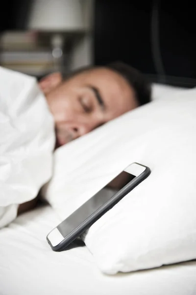 Jovem na cama perto de seu smartphone — Fotografia de Stock