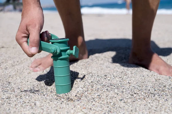 Человек устанавливает захватчик пляжного зонта — стоковое фото
