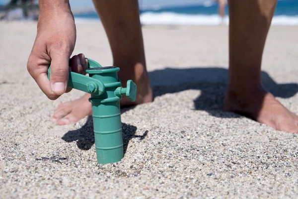 Man installing the grabber of a beach umbrella — Stock Photo, Image