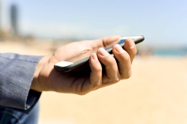 plaj yanındaki bir akıllı telefon kullanan adam