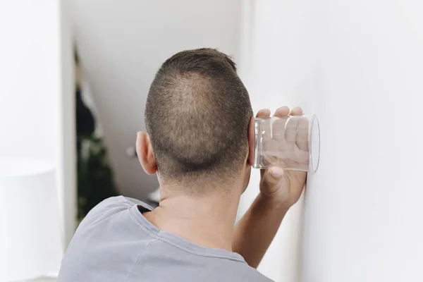 Young man trying to hear through the wall — Stock Photo, Image