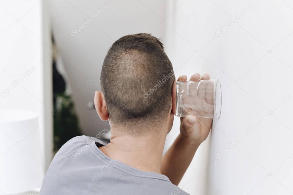 young man trying to hear through the wall