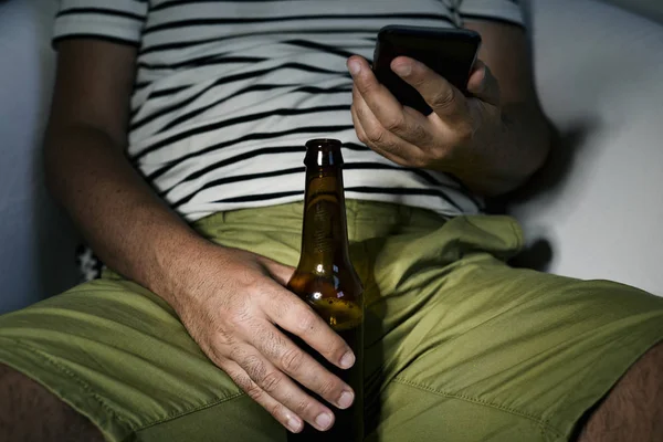 男はビールを飲みながら、彼の携帯電話を使用して — ストック写真