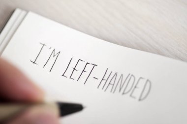 left-handed man writing the text I am left-handed clipart