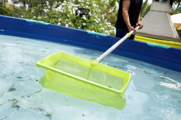 Jeune homme nettoyant une piscine portable — Photo