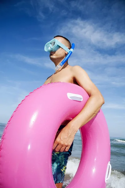 Uomo sulla spiaggia con maschera subacquea e anello di nuoto — Foto Stock