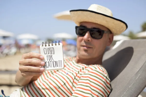 Mannen med en lapp med texten semesterstängt — Stockfoto